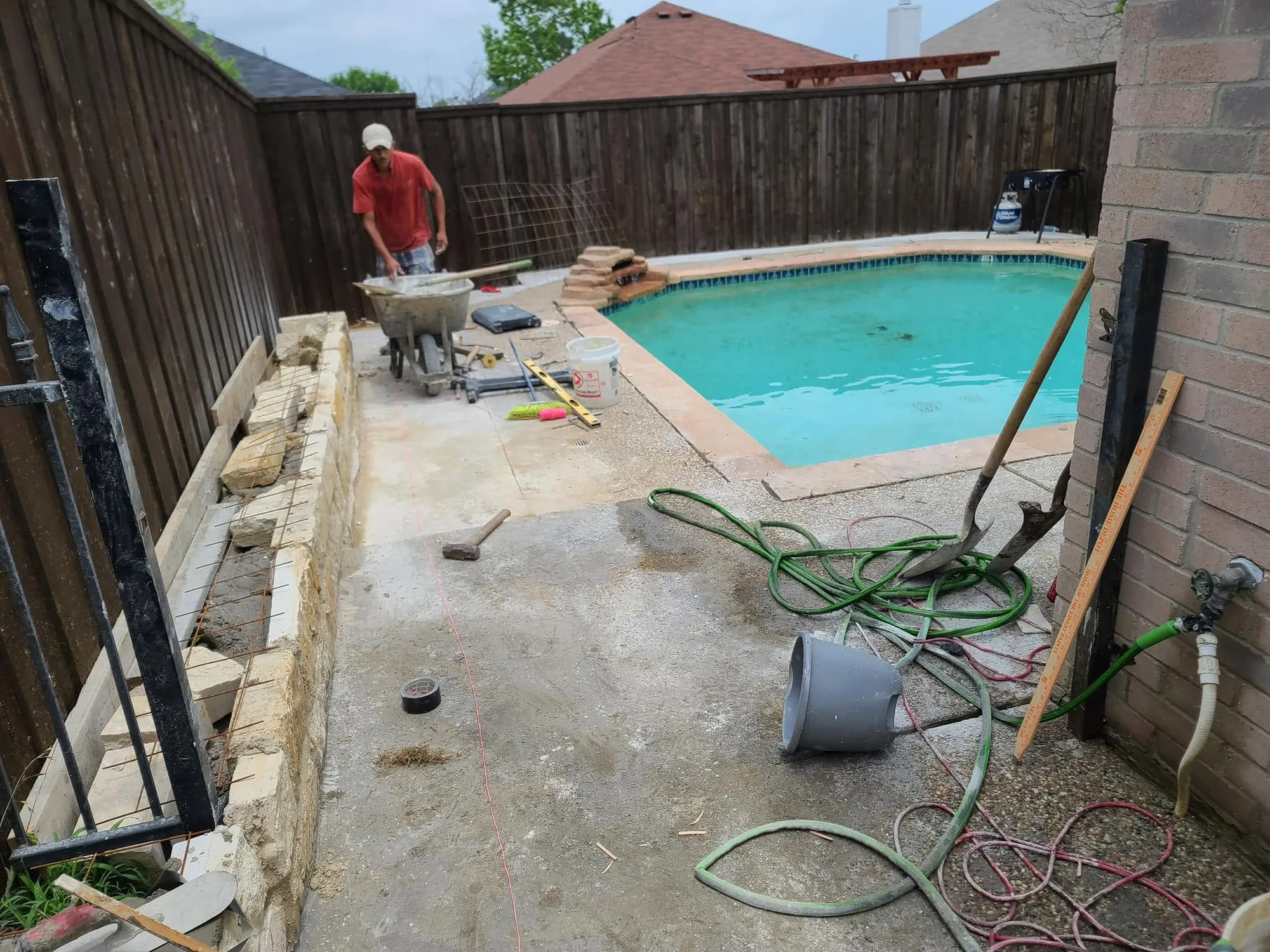 A crew member working from a wheelbarrow while finishing a concrete pool deck
